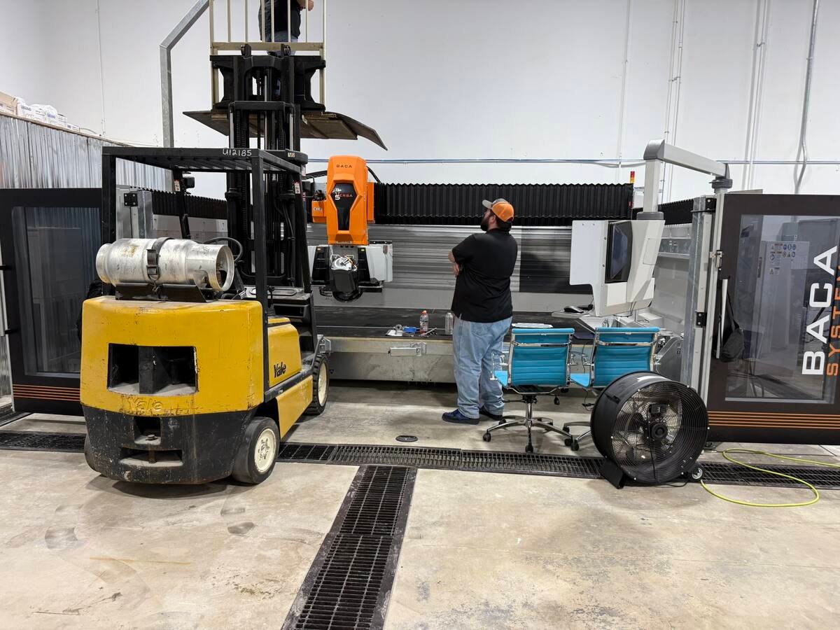 Technician beside CNC waterjet cutting machine in the QGS shop